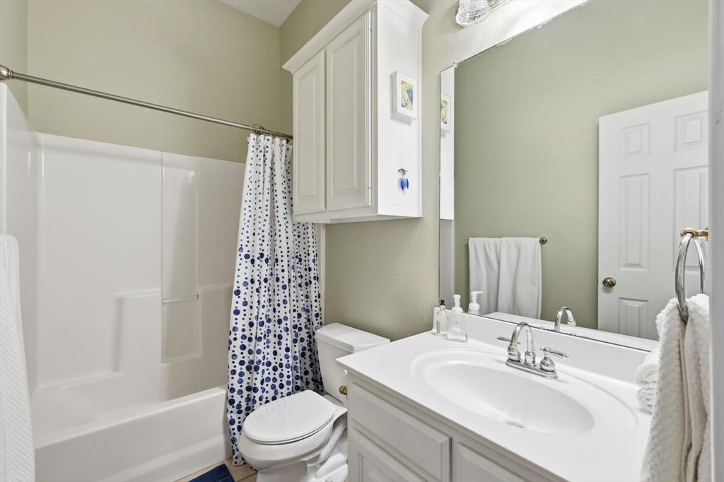 1311 Wilderness Street Denton, TX 76205 - Photo 29 of 40 a bathroom with a sink a toilet and shower curtain