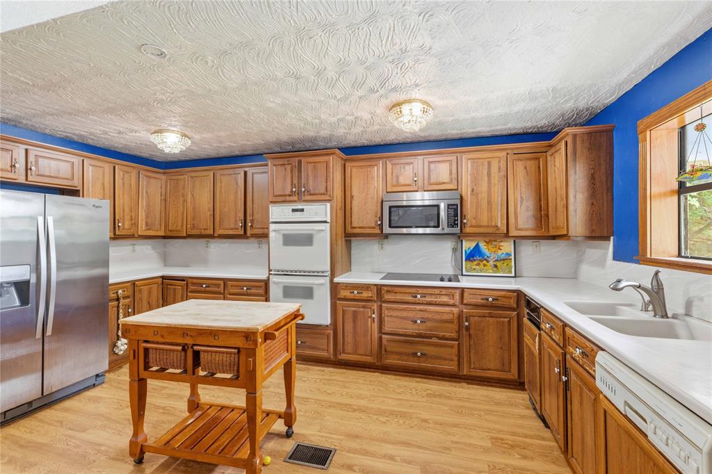 660 County Road 549 Mullin, TX 76864 - Photo 10 of 40 a kitchen with stainless steel appliances granite countertop a sink a stove a refrigerator cabinets and a dining table with wooden floor
