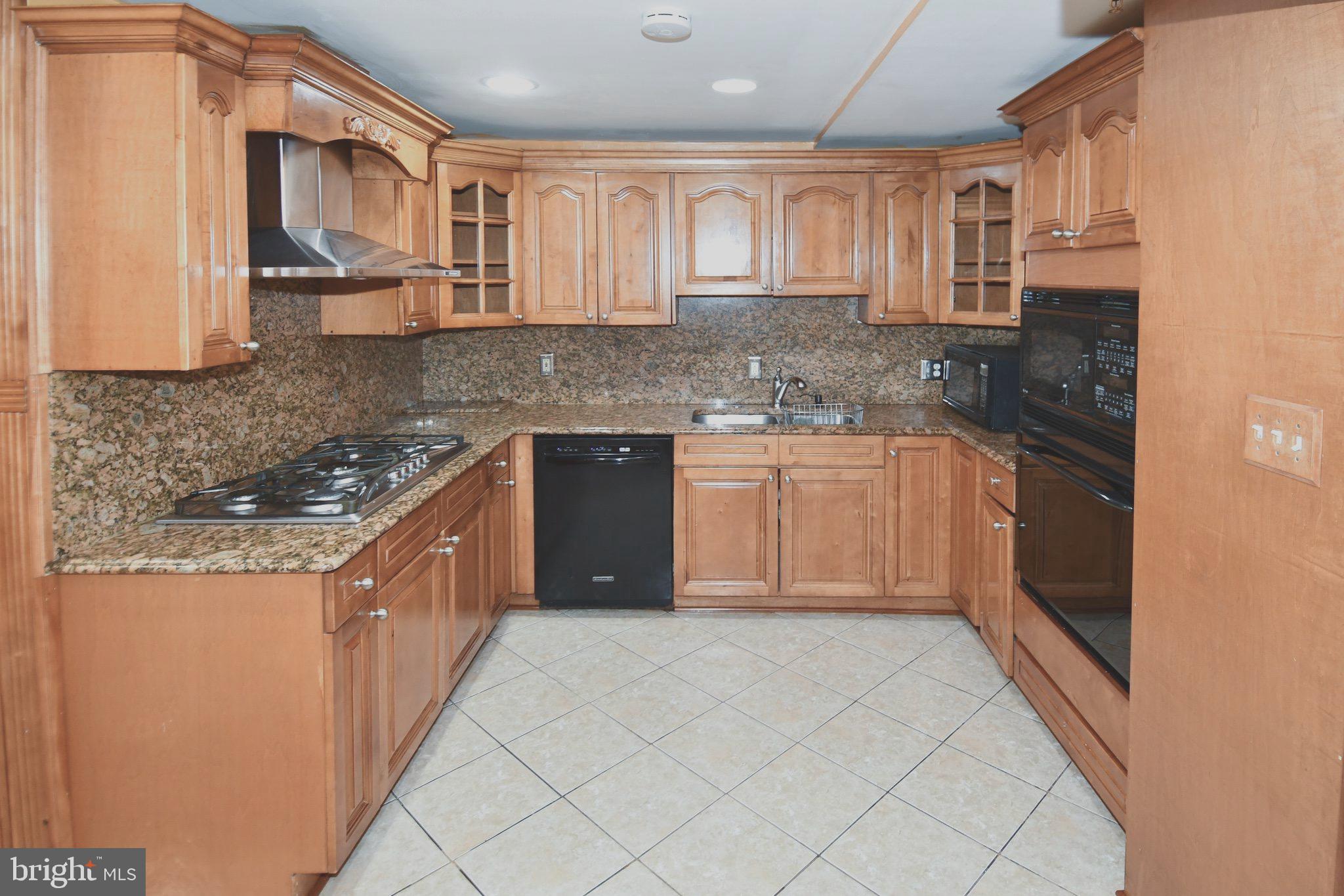 14528 Fairdale Road Silver Spring, MD 20905 - Photo 50 of 62 a kitchen with stainless steel appliances granite countertop a stove top oven a sink dishwasher and a refrigerator with wooden cabinets