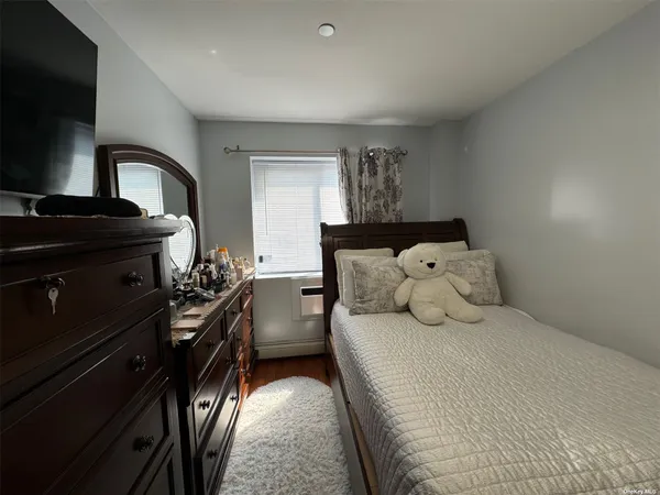 a bedroom with a bed and a flat tv screen on the dresser