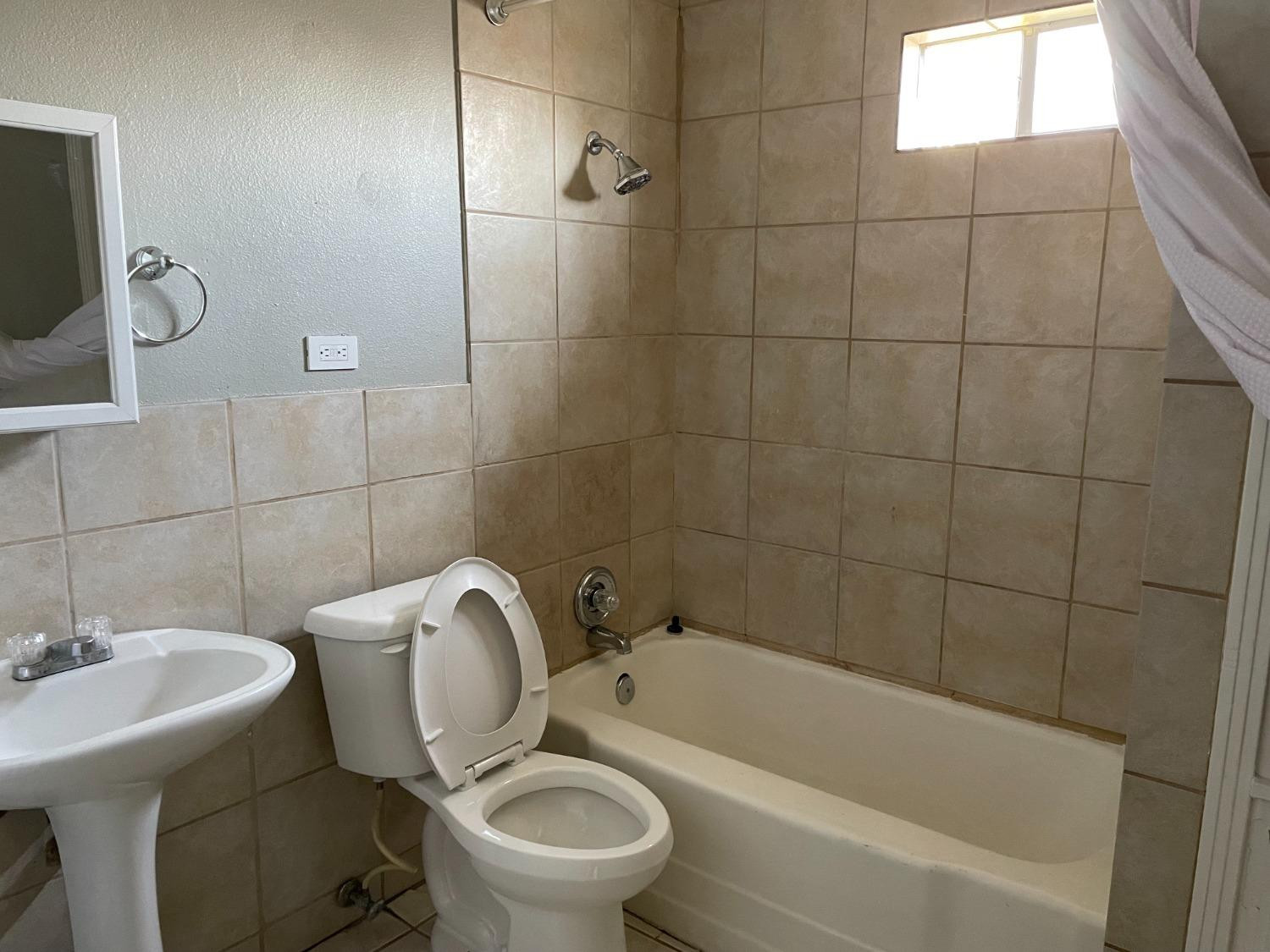 6501 Avenue T Lubbock, TX 79412 - Photo 20 of 20 a white toilet sitting next to a bathroom sink and tub