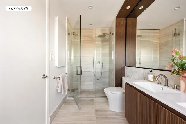 a bathroom with a double vanity sink toilet mirror and shower