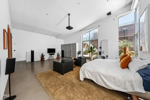 a bedroom with a bed a couch and a flat tv screen