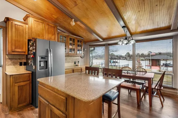 a kitchen with stainless steel appliances granite countertop a table chairs and a refrigerator