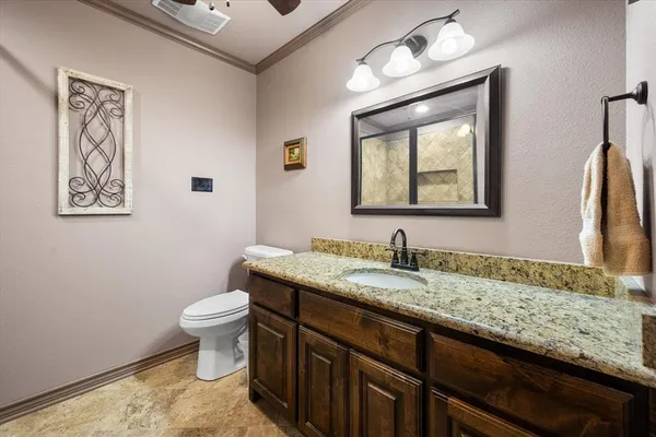 a bathroom with a granite countertop sink mirror vanity and toilet
