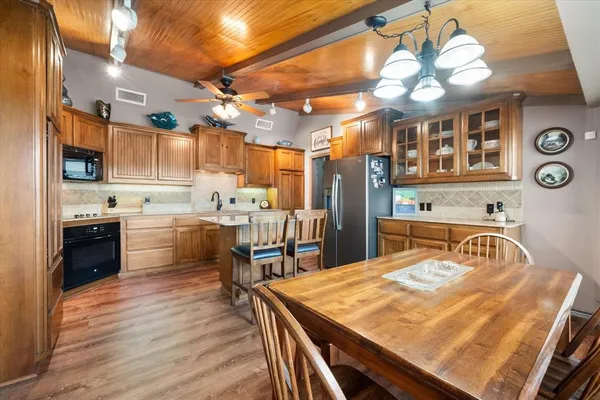 a kitchen with stainless steel appliances kitchen island granite countertop a stove a sink dishwasher and white cabinets with wooden floor