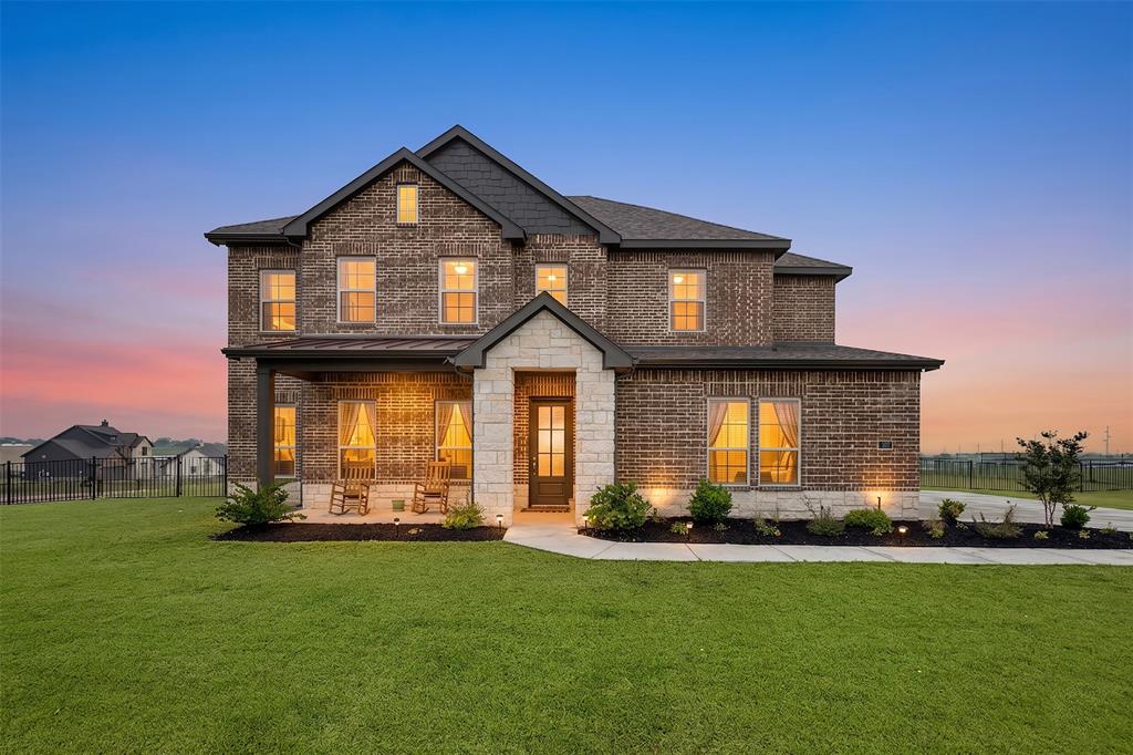 107 Yampa Court Rhome, TX 76078 - Photo 28 of 30 Two-story brick exterior with stone accents, a covered front porch, a dark asphalt shingle roof, and a meticulously maintained front lawn