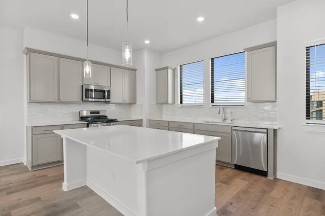 a large kitchen with stainless steel appliances granite countertop a sink a window and a refrigerator