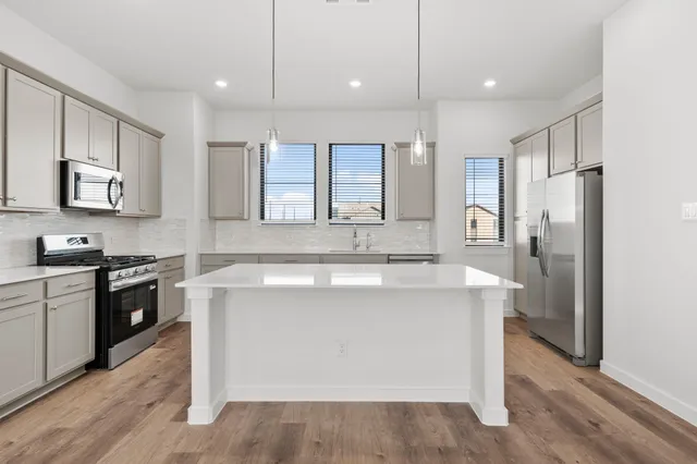 a kitchen with kitchen island granite countertop a sink stainless steel appliances and cabinets