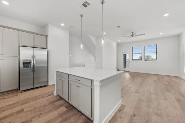 an empty room with wooden floor fan and windows