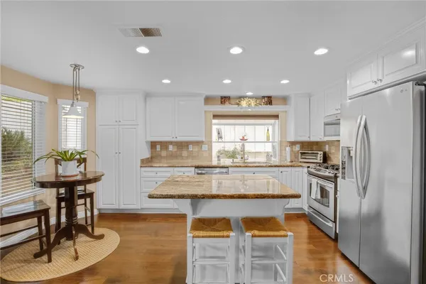 a kitchen with kitchen island stainless steel appliances wooden floor dining table and chairs