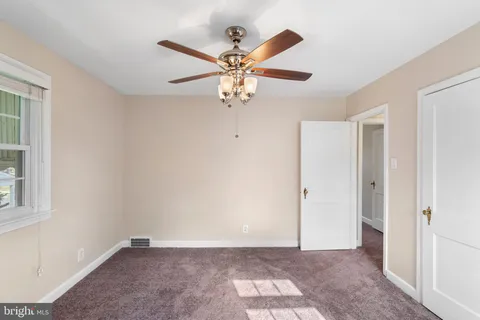 a view of an empty room with window and a ceiling fan