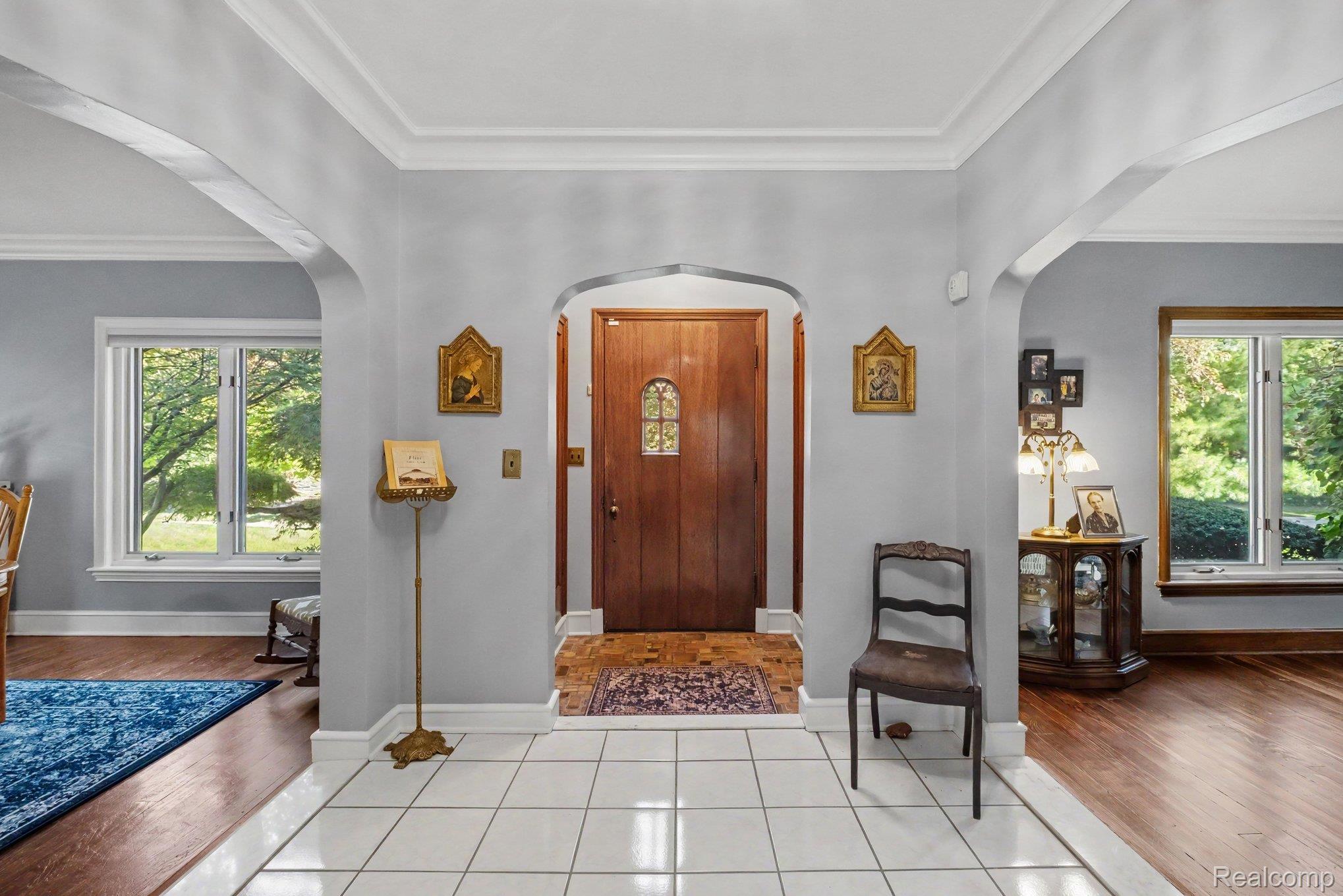 2030 Hampden Road Flint, MI 48503 - Photo 4 of 34 Entryway featuring white tile flooring, arched doorways, a wood-finish entry door with glass inserts, and crown molding