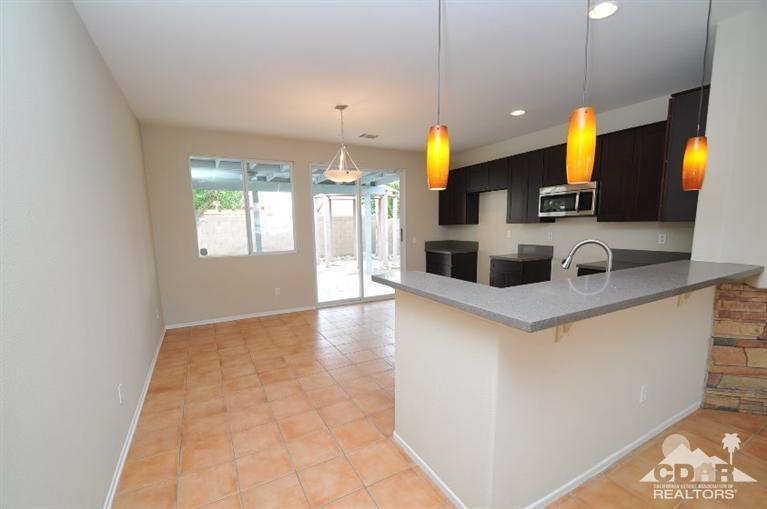 47534 Stampede Trail Indio, CA 92201 - Photo 4 of 17 a kitchen with kitchen island a counter top space appliances and a living room view