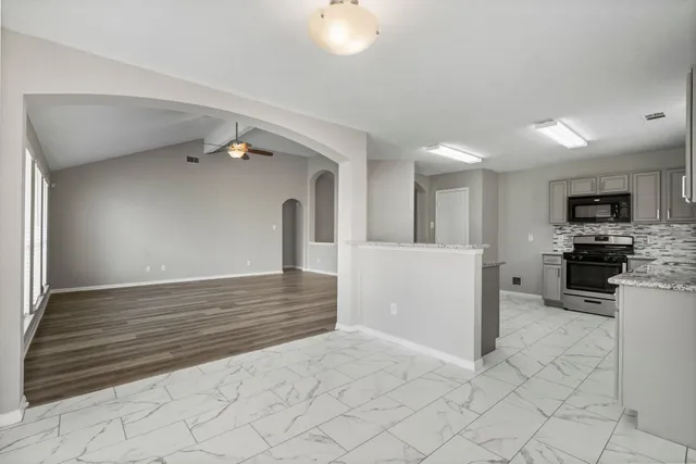 a kitchen with granite countertop a refrigerator and a stove top oven