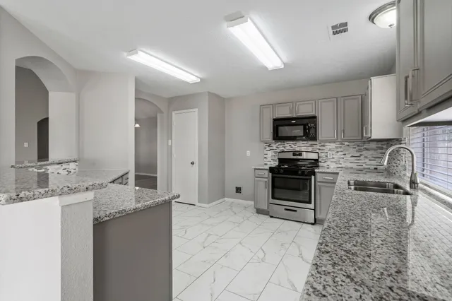 a kitchen with stainless steel appliances granite countertop a sink stove and refrigerator