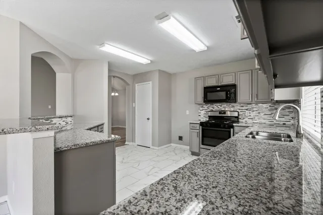 a kitchen with stainless steel appliances granite countertop a stove top oven a sink dishwasher a refrigerator and cabinets with wooden floor