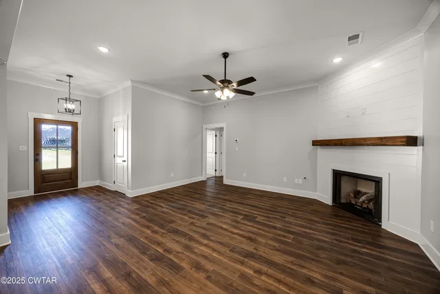 a view of an empty room with wooden floor fireplace and a window