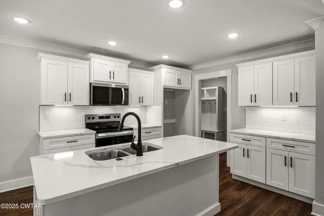 a large kitchen with stainless steel appliances kitchen island a stove a refrigerator a sink and dishwasher with wooden floor