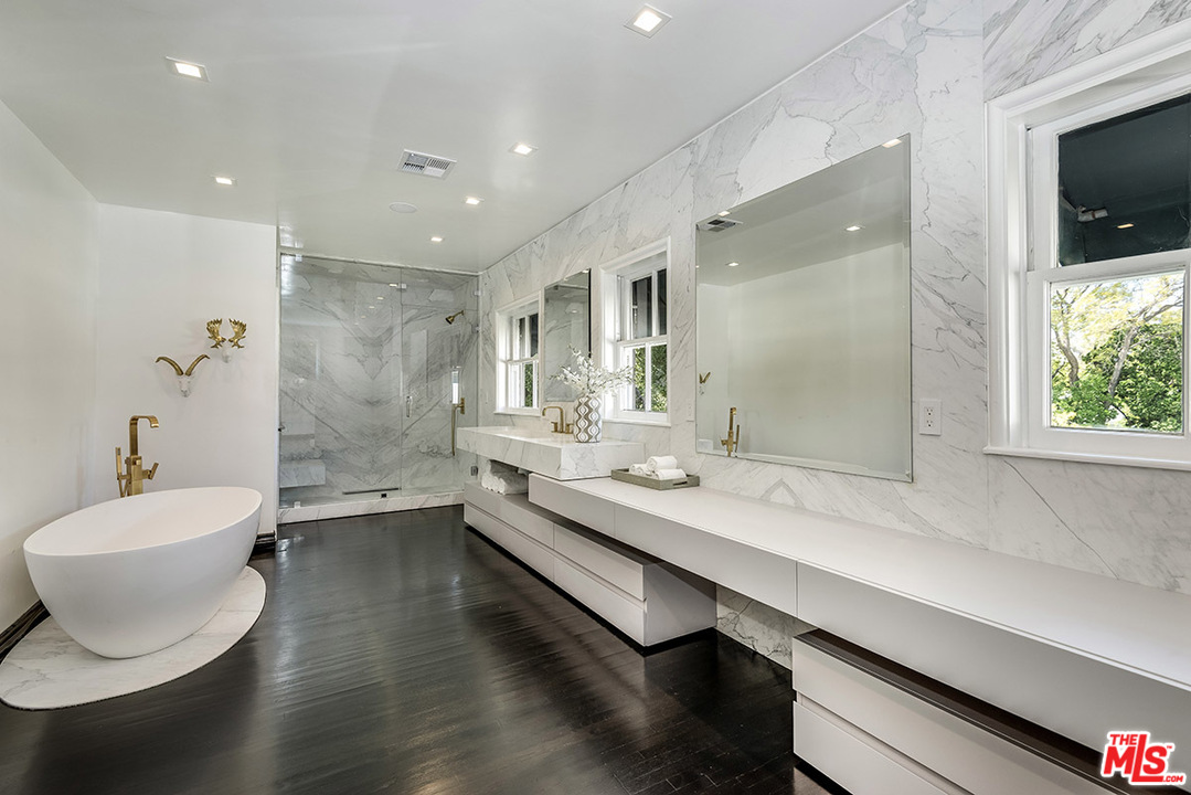 243 Delfern Drive Los Angeles, CA 90077 - Photo 17 of 32 a bathroom with a double vanity sink a mirror and a bathtub