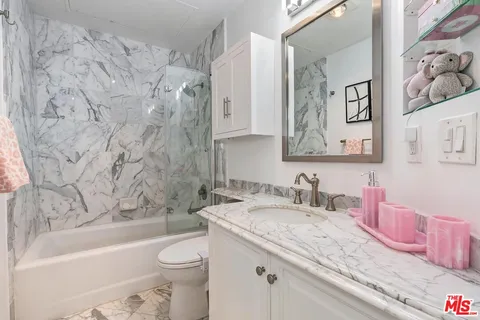 a bathroom with a granite countertop bathtub sink vanity mirror and toilet