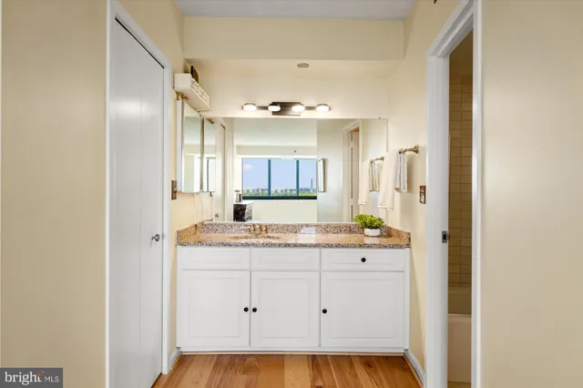 a bathroom with a granite countertop sink a mirror and a bathtub