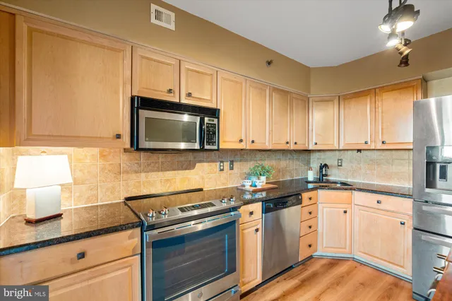a kitchen with granite countertop white cabinets stainless steel appliances and a sink