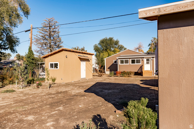 4658 Box Elder Street Salt Lake City, UT 84107 - Photo 15 of 17 Spacious backyard featuring a detached accessory building with a window and a main residence with brown siding, white trim, and a rear entrance with wooden steps