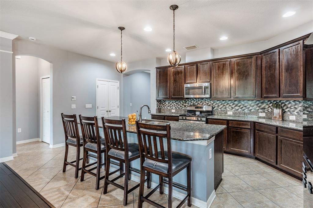 6908 Covington Stone Avenue Apollo Beach, FL 33572 - Photo 11 of 60 a kitchen with stainless steel appliances kitchen island granite countertop a sink a stove a dining table and chairs