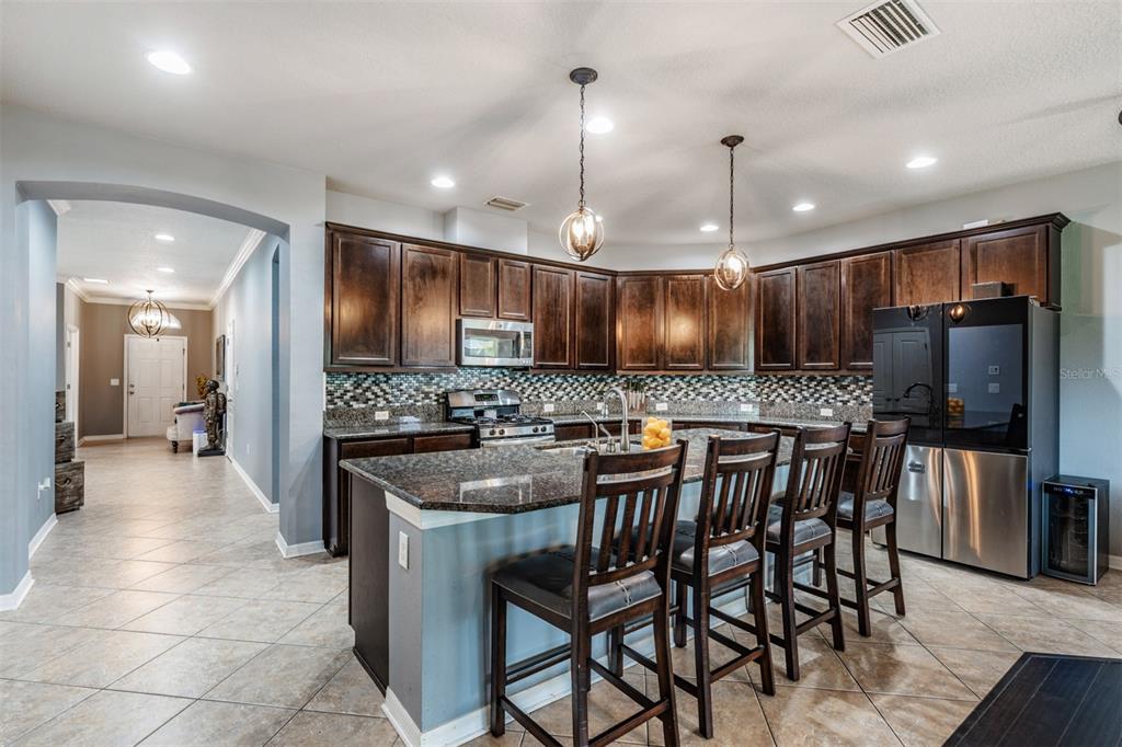 6908 Covington Stone Avenue Apollo Beach, FL 33572 - Photo 13 of 60 a kitchen with stainless steel appliances granite countertop a stove a sink a oven a dining table and chairs