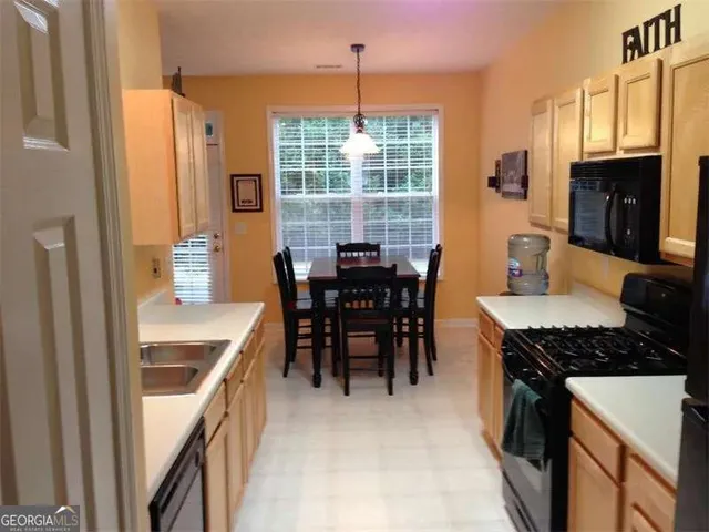 a kitchen with stainless steel appliances granite countertop a stove a sink dishwasher a dining table and chairs with wooden floor