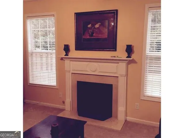 a view of an empty room with a fireplace and wooden floor