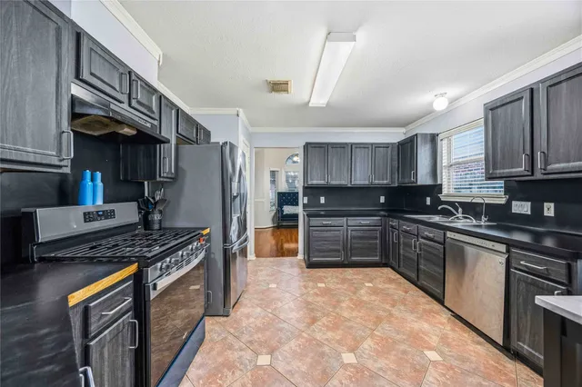 a kitchen with stainless steel appliances granite countertop a stove top oven a sink dishwasher a refrigerator and cabinets with wooden floor