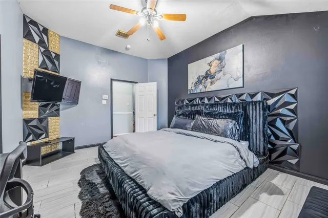 a bedroom with a bed and a flat tv screen on dresser