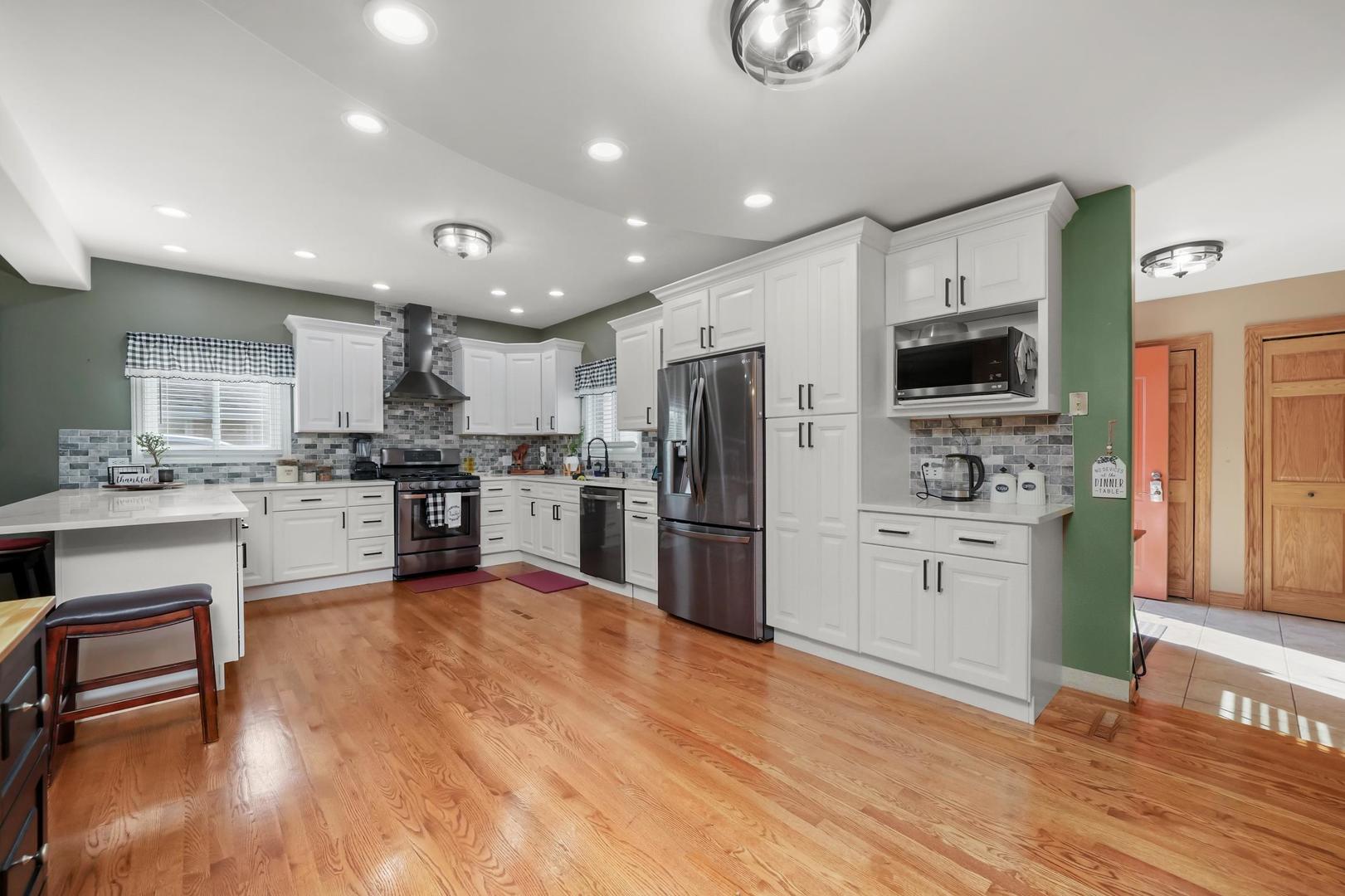 5907 West 109th Street Chicago Ridge, IL 60415 - Photo 11 of 45 a kitchen with a refrigerator a stove top oven a sink dishwasher and white cabinets with wooden floor