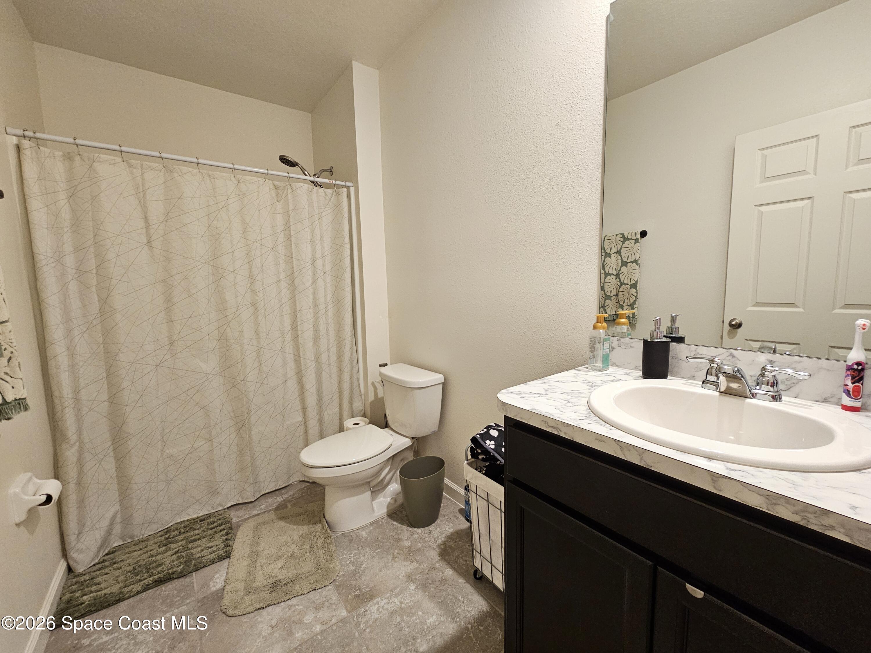 456 Snook Place Cocoa, FL 32927 - Photo 13 of 15 a bathroom with a sink a toilet a mirror and shower curtain