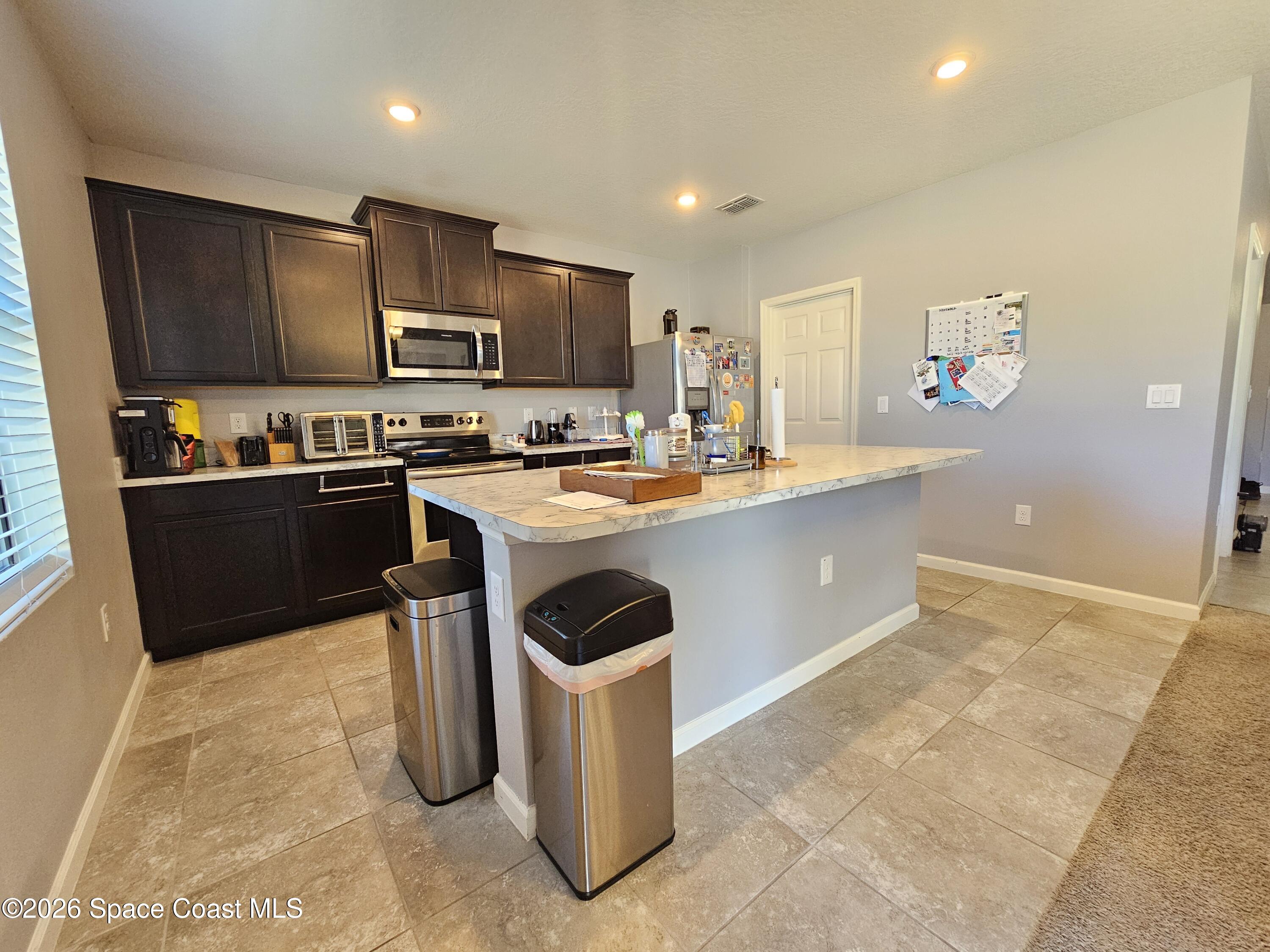 456 Snook Place Cocoa, FL 32927 - Photo 6 of 15 a kitchen with stainless steel appliances granite countertop a stove a sink a refrigerator a microwave oven with a dining table and chairs