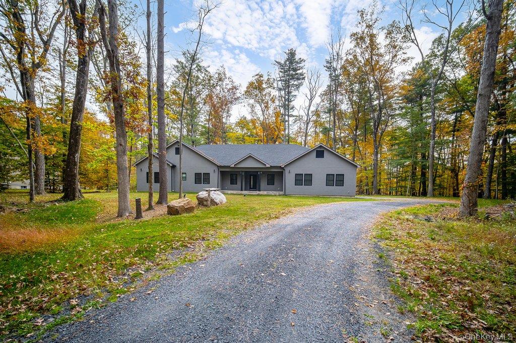 Single story home with gravel driveway, a porch, a front yard, and stucco siding