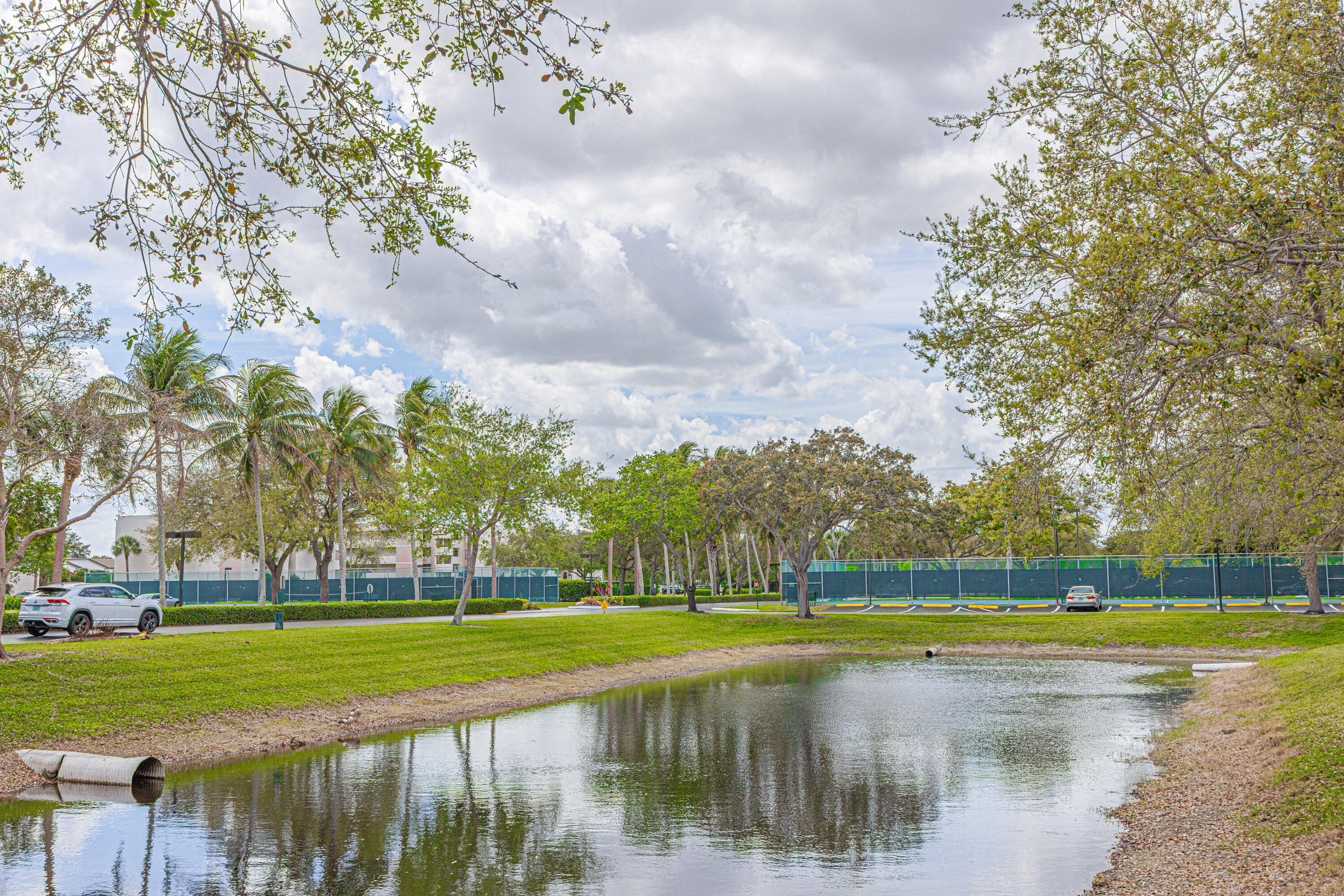 5750 Camino Del Sol, Unit 202 Boca Raton, FL 33433 - Photo 23 of 24 a view of swimming pool with a garden and trees