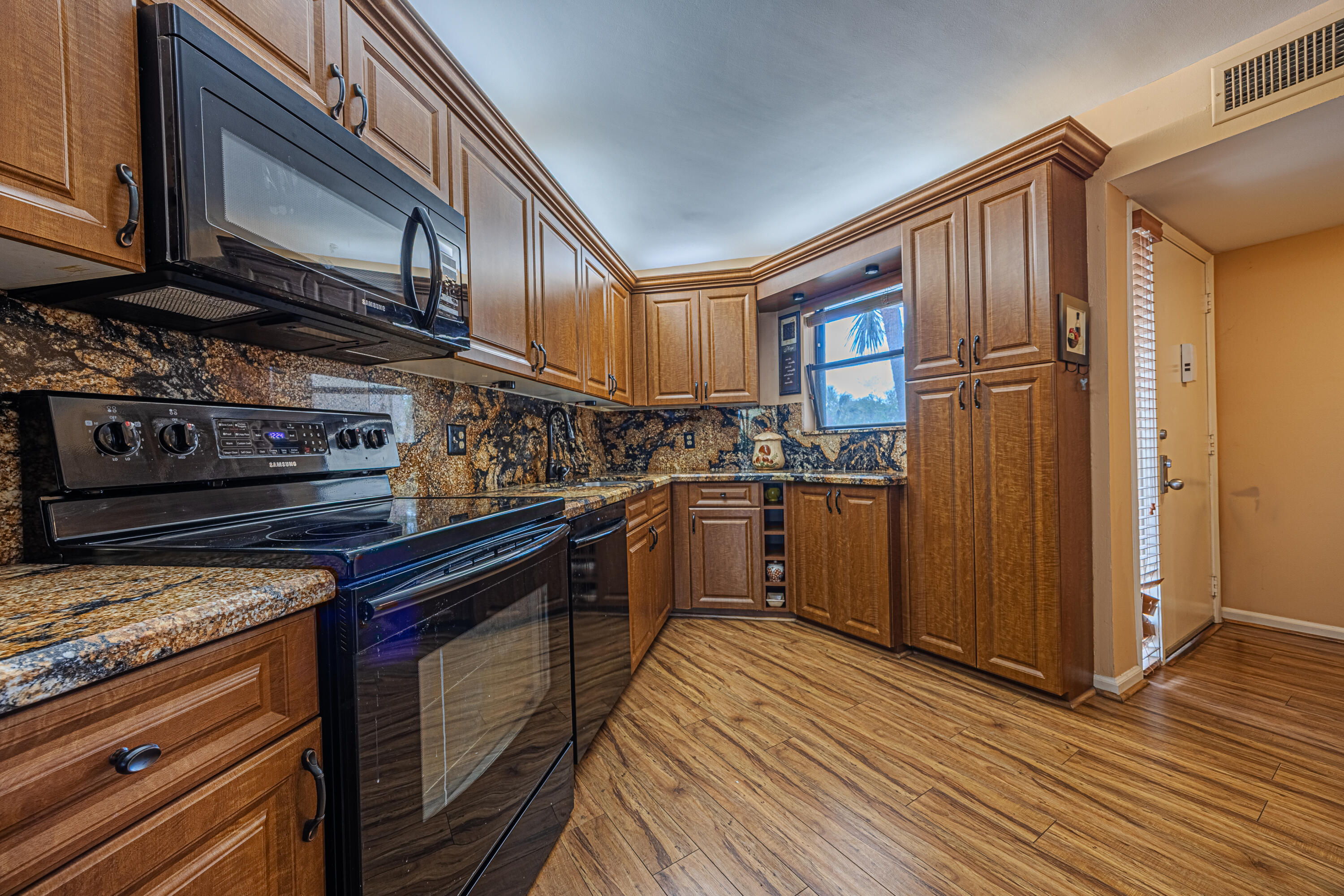 5750 Camino Del Sol, Unit 202 Boca Raton, FL 33433 - Photo 5 of 24 a kitchen with granite countertop wooden cabinets stainless steel appliances and a window