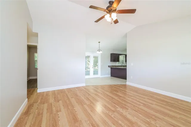 a view of a kitchen with wooden floor a ceiling fan and windows