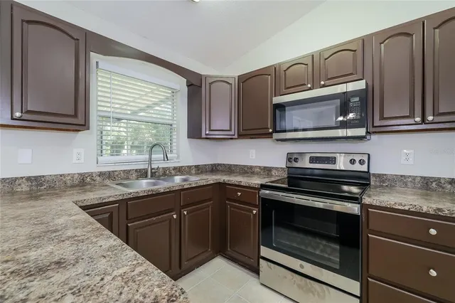 a kitchen with granite countertop a sink stove and microwave