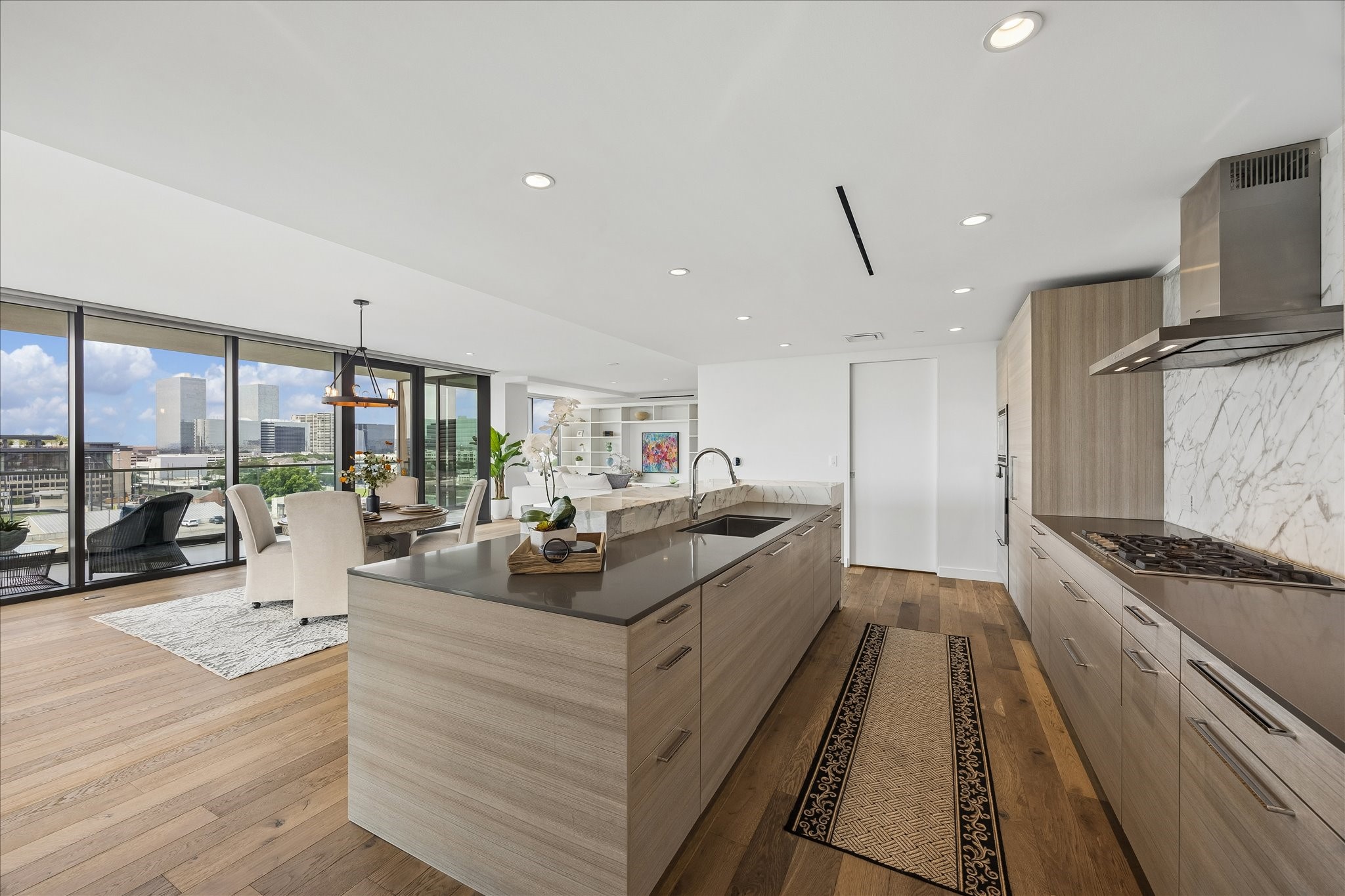 3433 Westheimer Road, Unit 702 Houston, TX 77027 - Photo 9 of 48 Open-concept kitchen and dining area features Poggenpohl cabinetry that seamlessly integrates the refrigerator and dishwasher for a sophisticated, streamlined aesthetic.