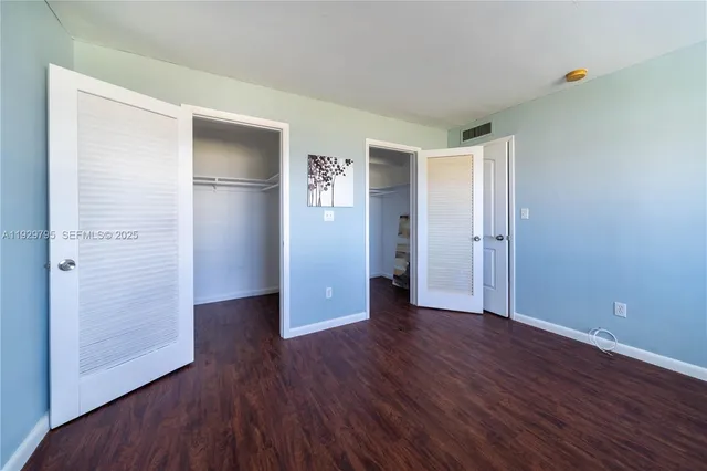 an empty room with wooden floor & closet area