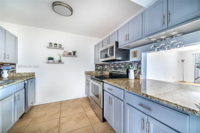 a kitchen with granite countertop a sink a stove and cabinets