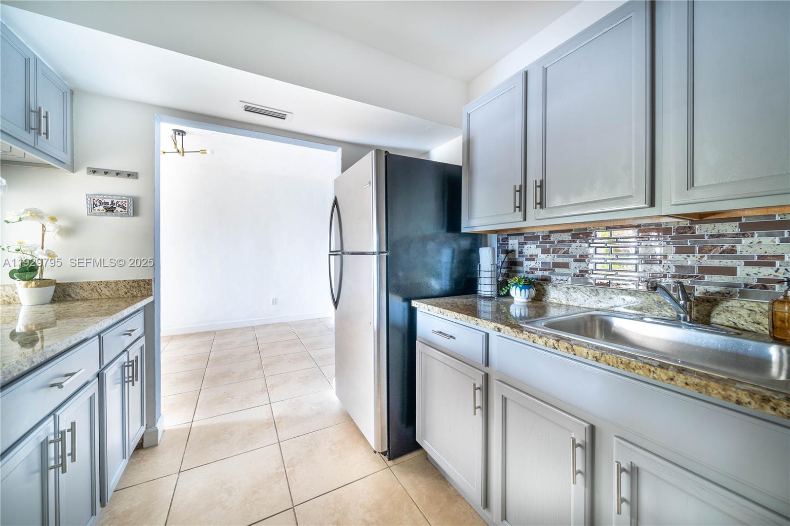 1855 Northeast 121st Street, Unit 32 North Miami, FL 33181 - Photo 7 of 22 a kitchen with a sink a refrigerator and cabinets