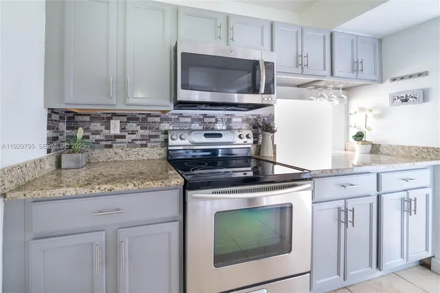 a kitchen with granite countertop white cabinets and black appliances