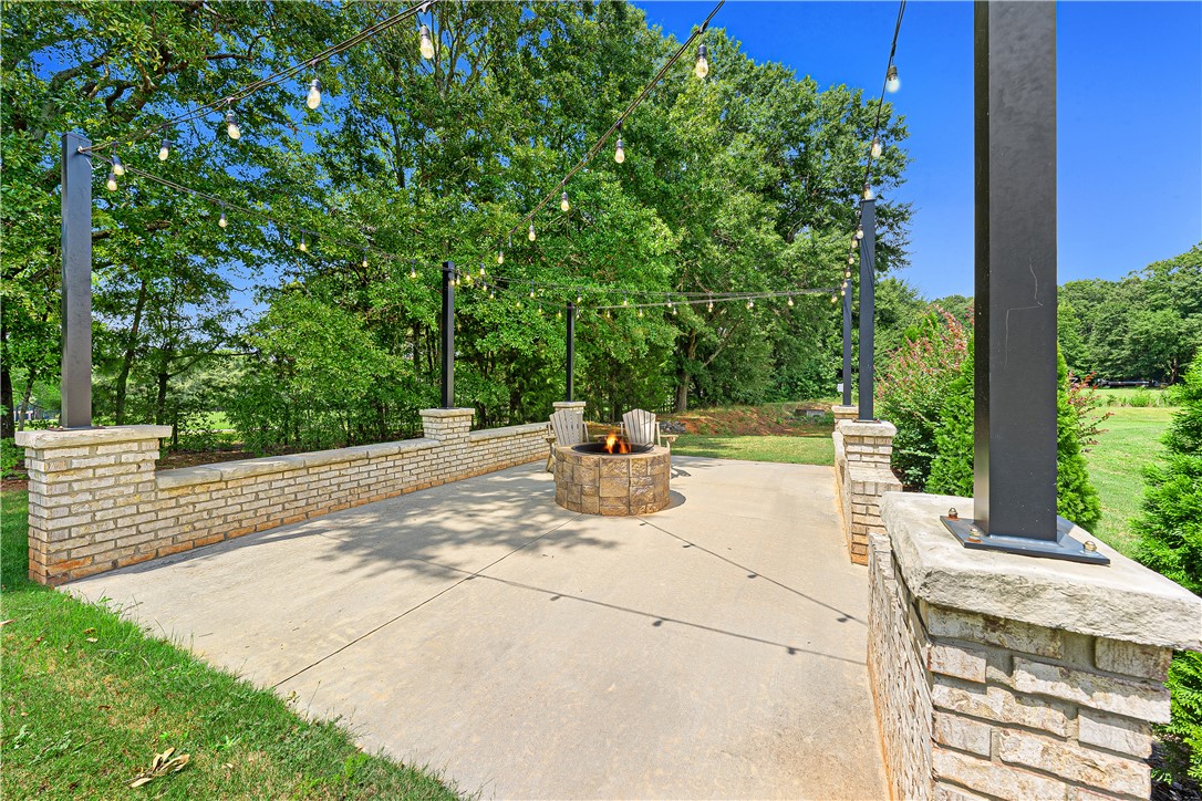 261 Scenic Road Anderson, SC 29621 - Photo 34 of 35 A spacious concrete patio features a built-in fire pit surrounded by brick retaining walls.