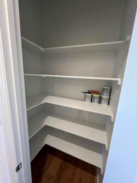 1407 Cartona Road Fate, TX 75087 - Photo 13 of 21 Corner pantry featuring multiple white built-in shelves and wood-finish flooring