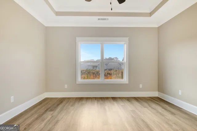 an empty room with a ceiling fan and wooden floor